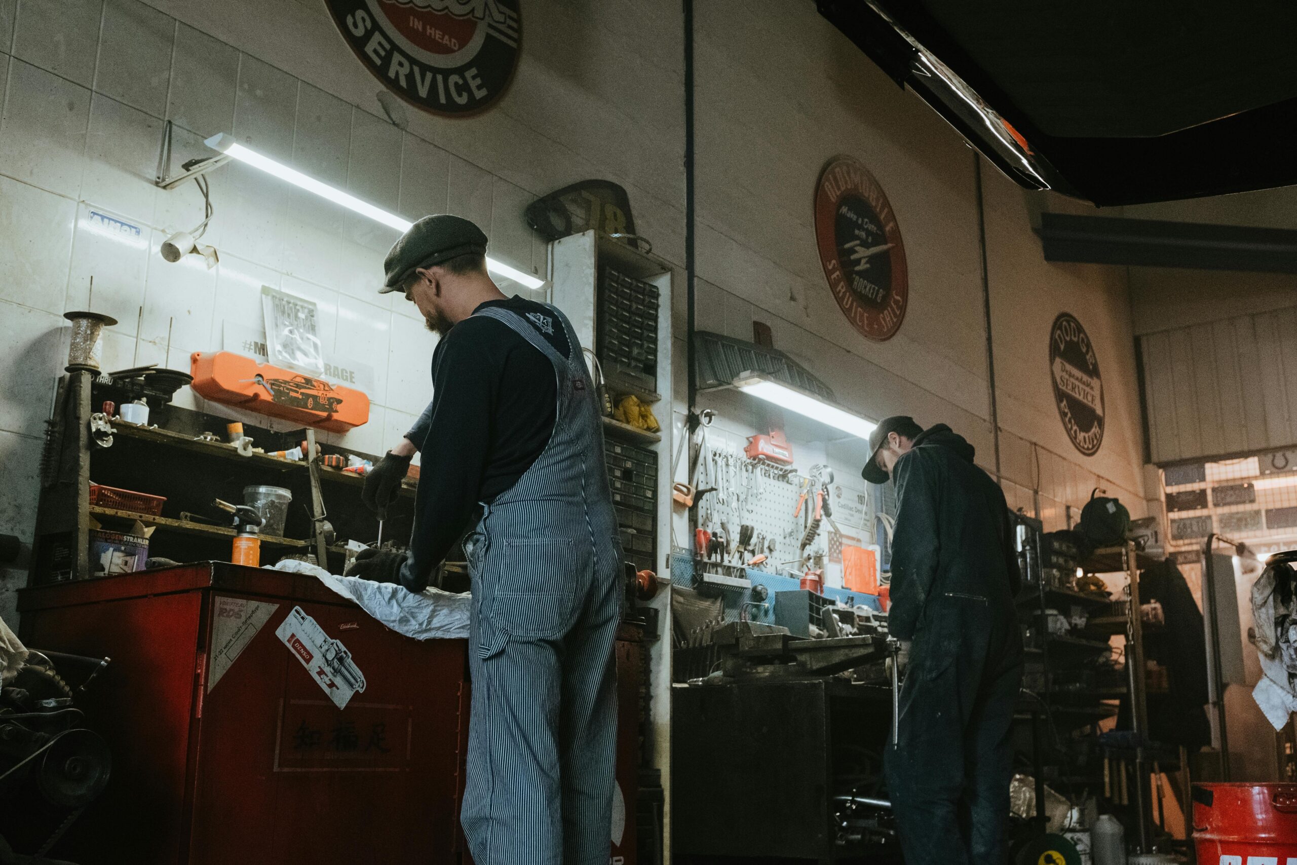 Two mechanics in a garage working on vehicle repair and maintenance.