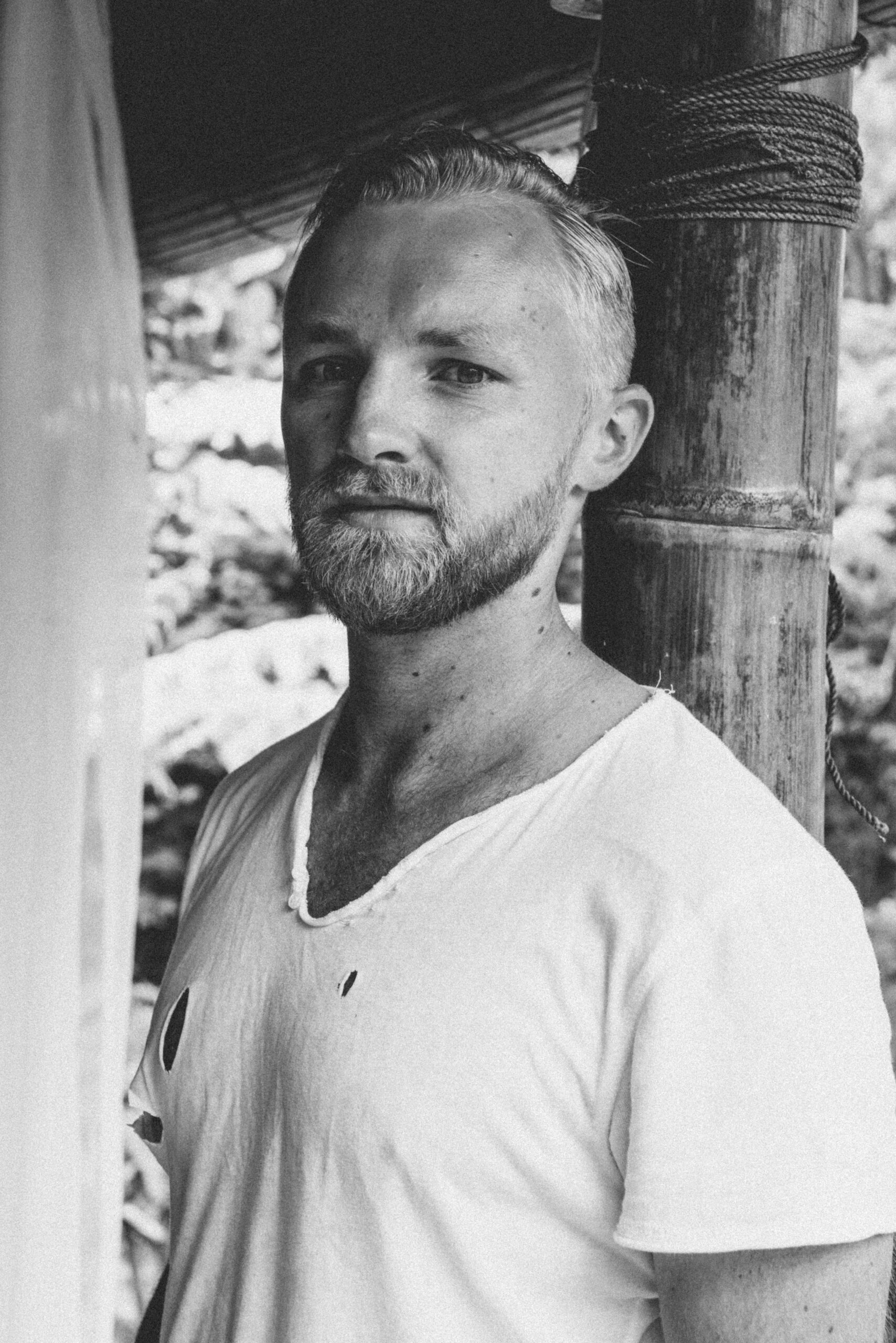 Artistic black and white portrait of a man with facial hair and casual style.